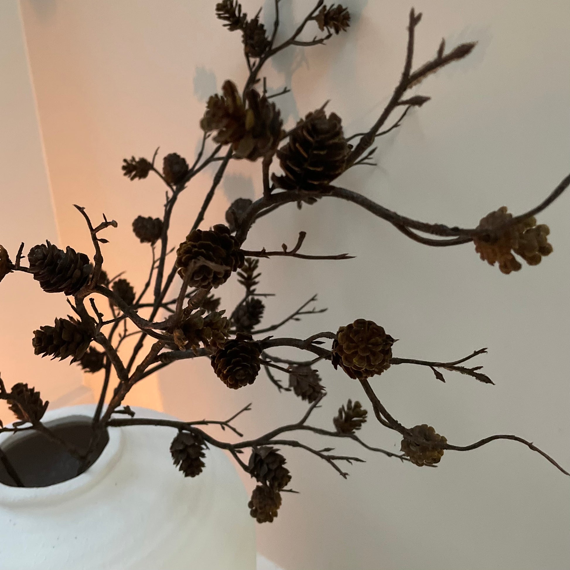 Faux pinecone spray with realistic mini pine cones. Styled in a white ceramic vase.