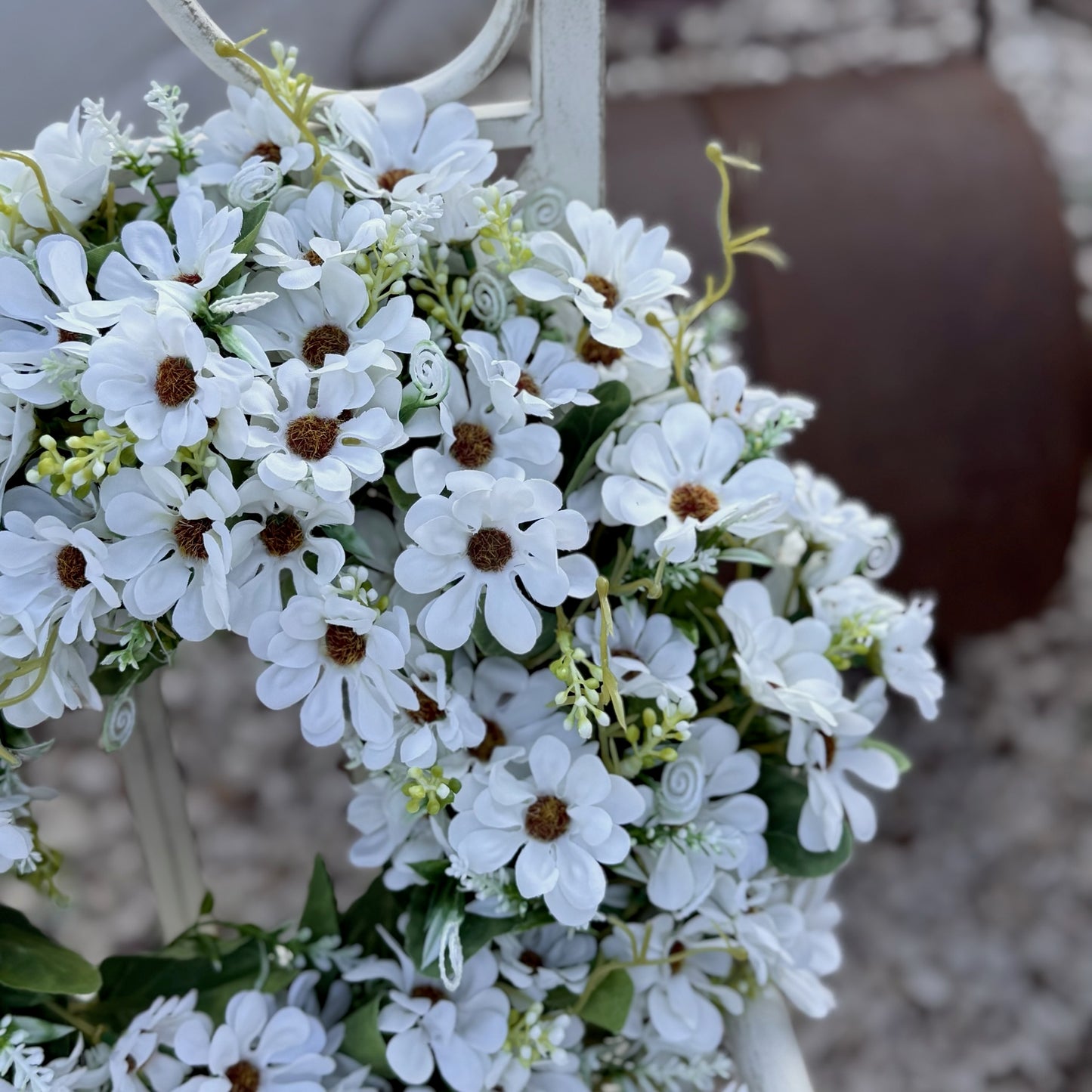 Decorative faux floral wreath with daisies and gentle greenery, bringing a fresh, joyful feel to a home.