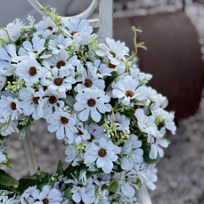 Decorative faux floral wreath with daisies and gentle greenery, bringing a fresh, joyful feel to a home.