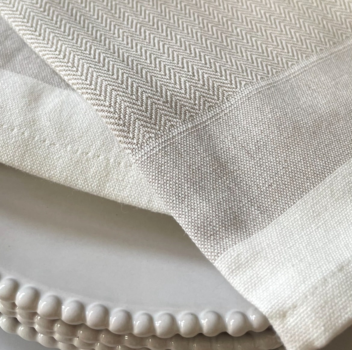 Close up of herringbone weave on taupe cotton napkin. 