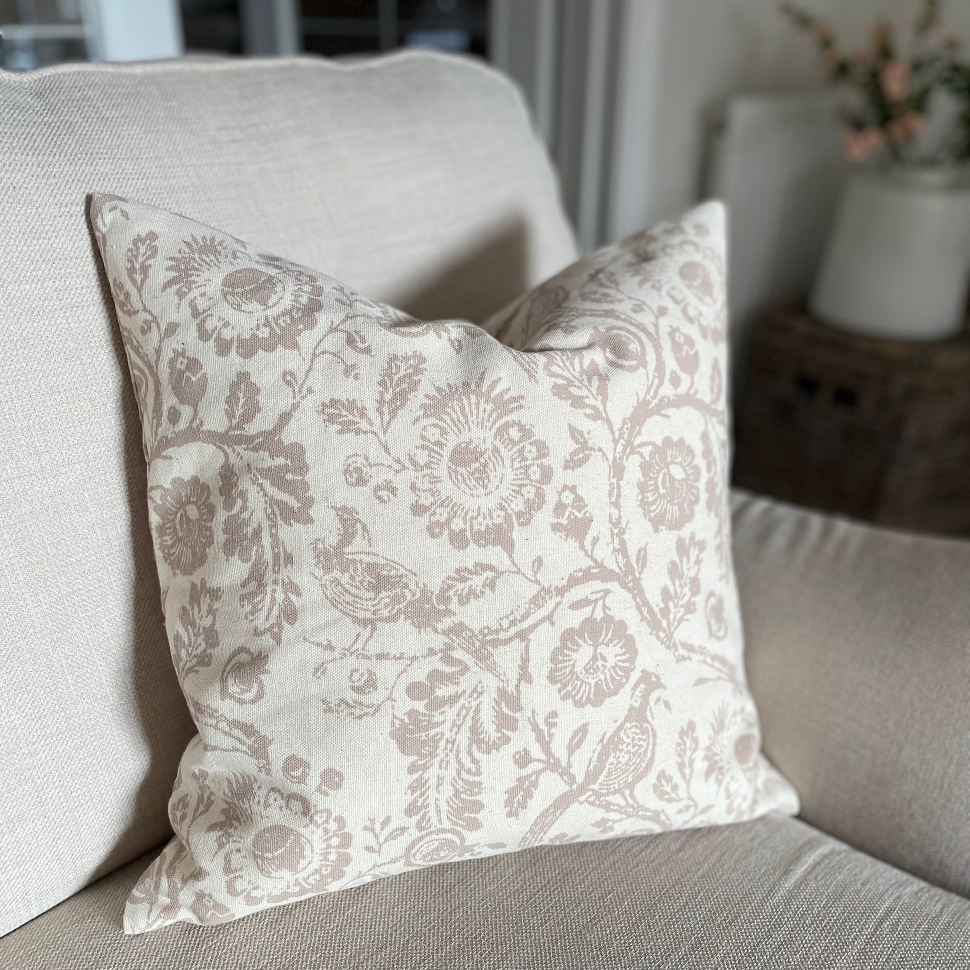 Taupe patterned cushion with a subtle country inspired print styled on a neutral sofa.