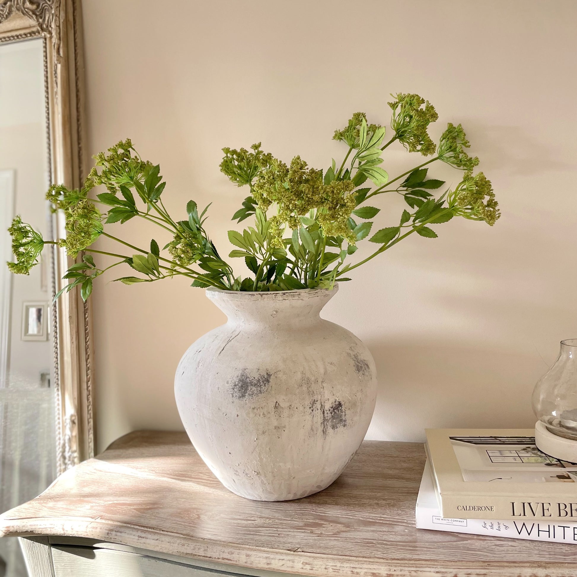 Faux Cow Parsley stem styled in a stone vase on a rustic console table, white books and a lantern.