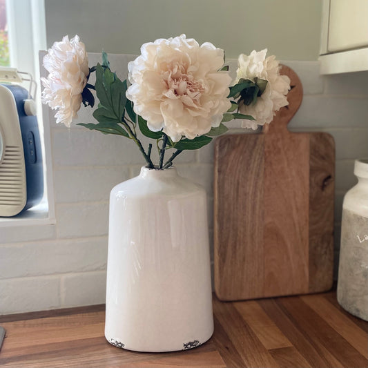 Cream crackle glazed ceramic vase with textured finish, styled with flowers on a rustic kitchen worktop.
