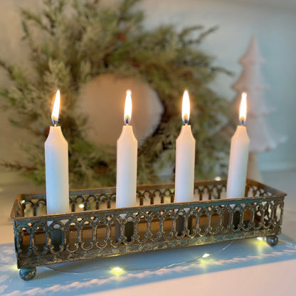 Rustic four candle tin holder styled on mantlepiece. With a wreath in the background.