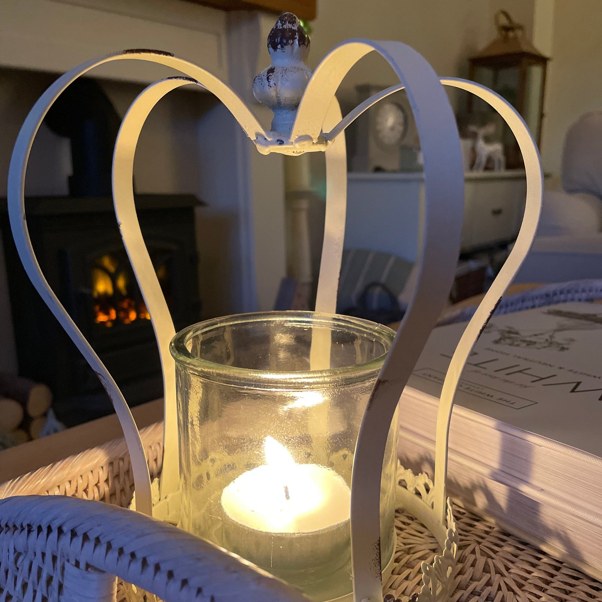 Antique style distressed white metal crown candle holder with removable glass insert, styled on a rattan tray.