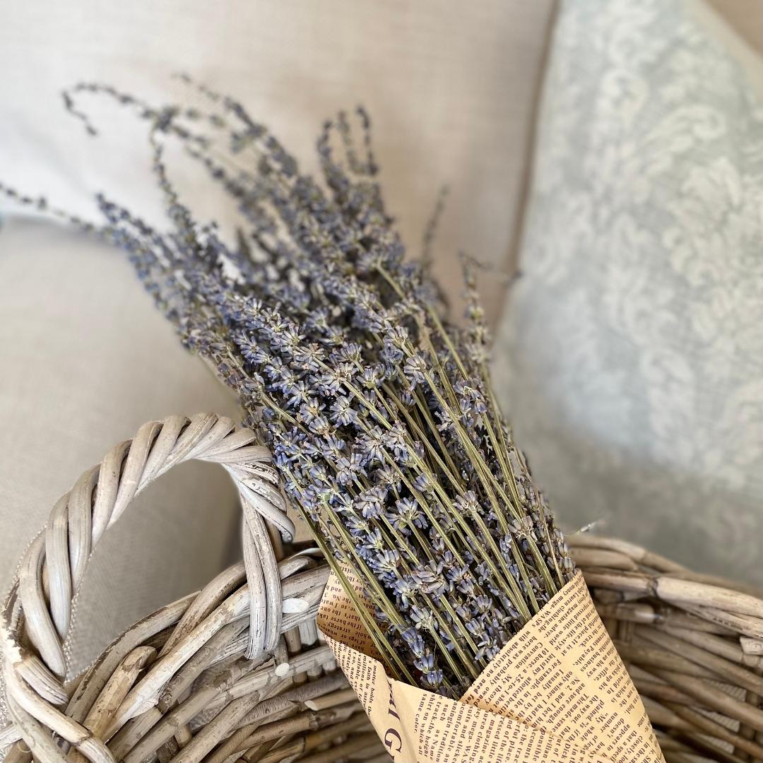 Dried lavender bunch wrapped in brown paper and tied with jute string, styled in a rattan basket.