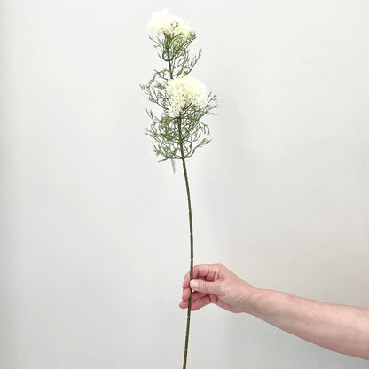 Faux elderflower spray with two clusters of white buds held on a white background.