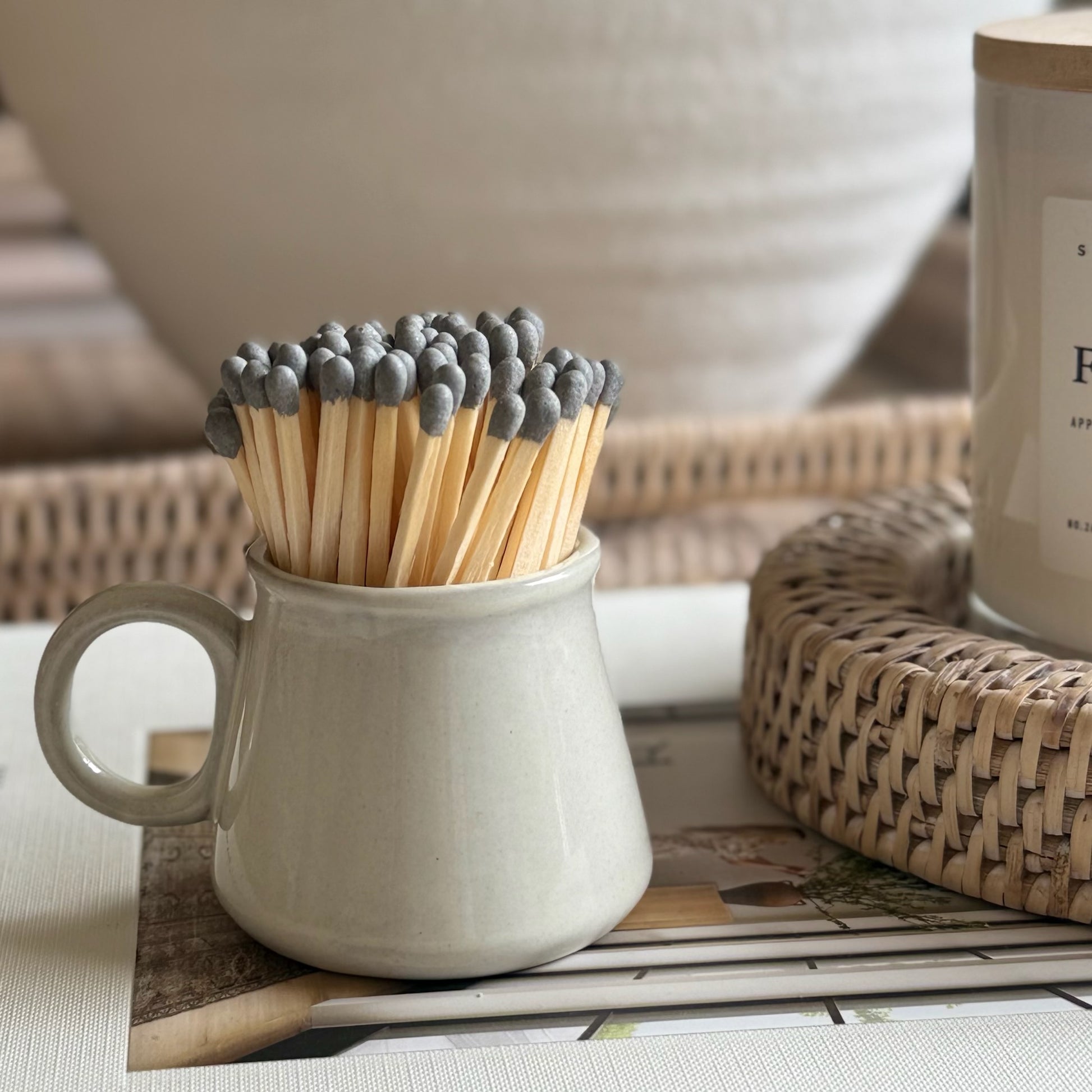 Hand finished grey ceramic espresso style match striker filled with strike-anywhere matches, styled on a neutral coffee table.