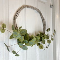 Wreath made of green leaves on a white door.