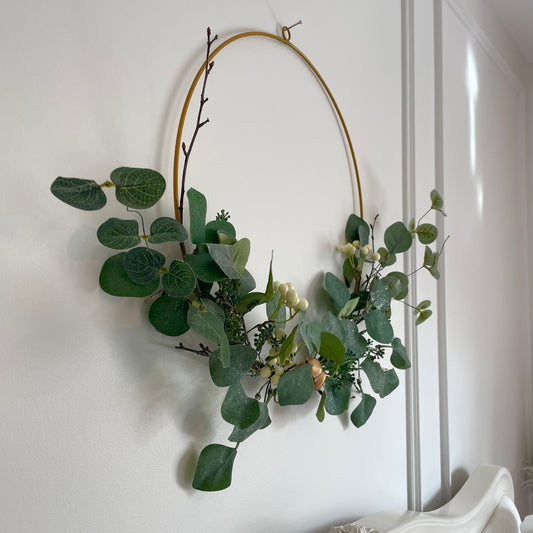 Eucalyptus half wreath on antique gold ring with bells and white berries.