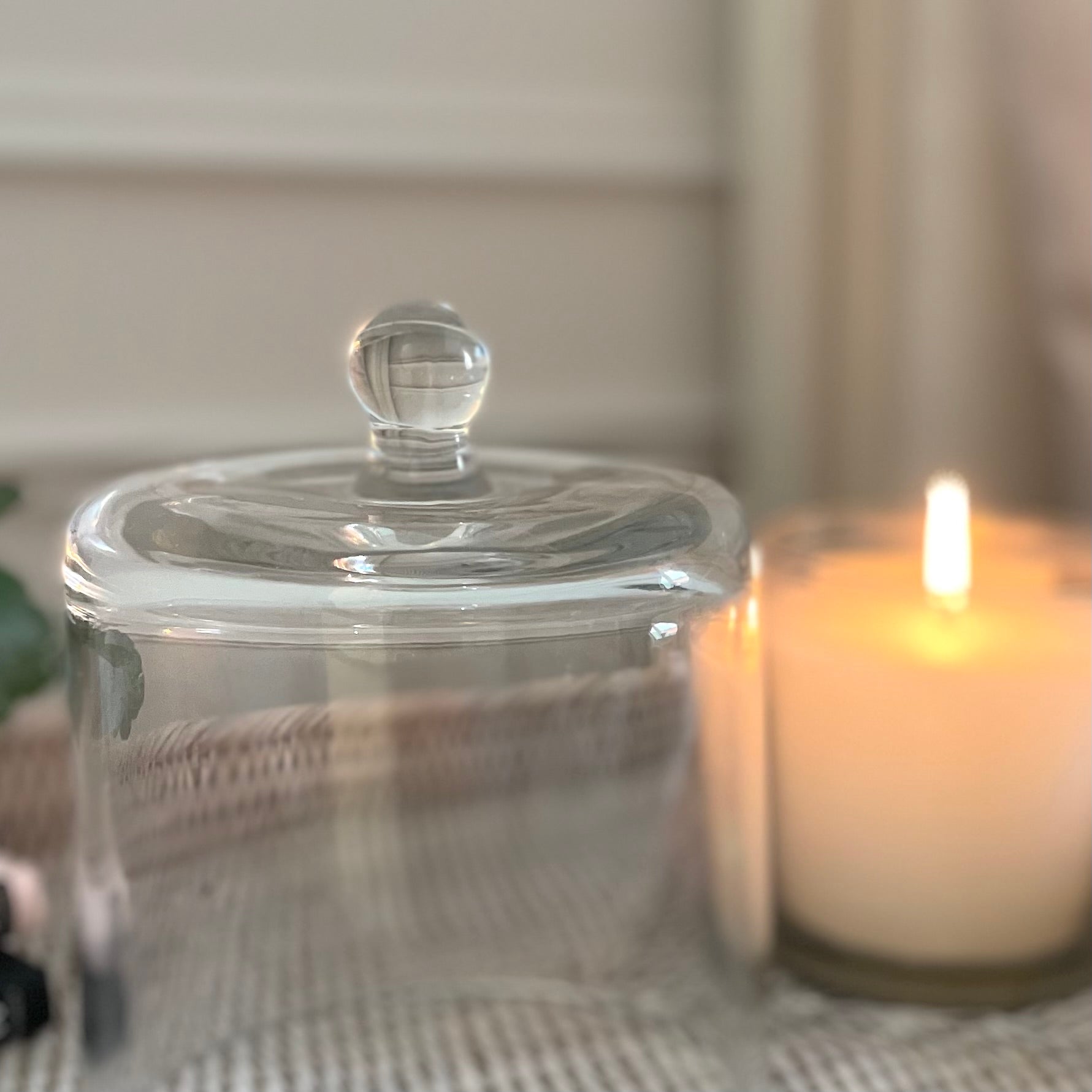 Clear glass cloche dome styled over a candle on a tray for elegant home display.