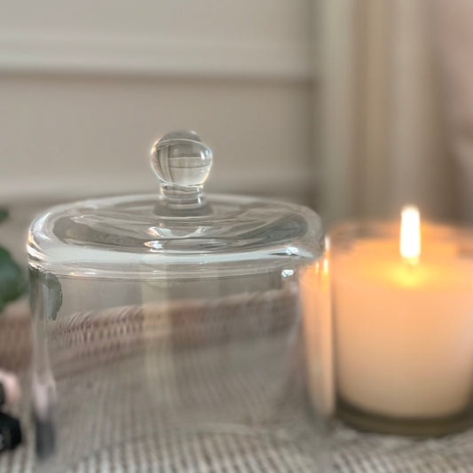 Clear glass cloche dome styled over a candle on a tray for elegant home display.