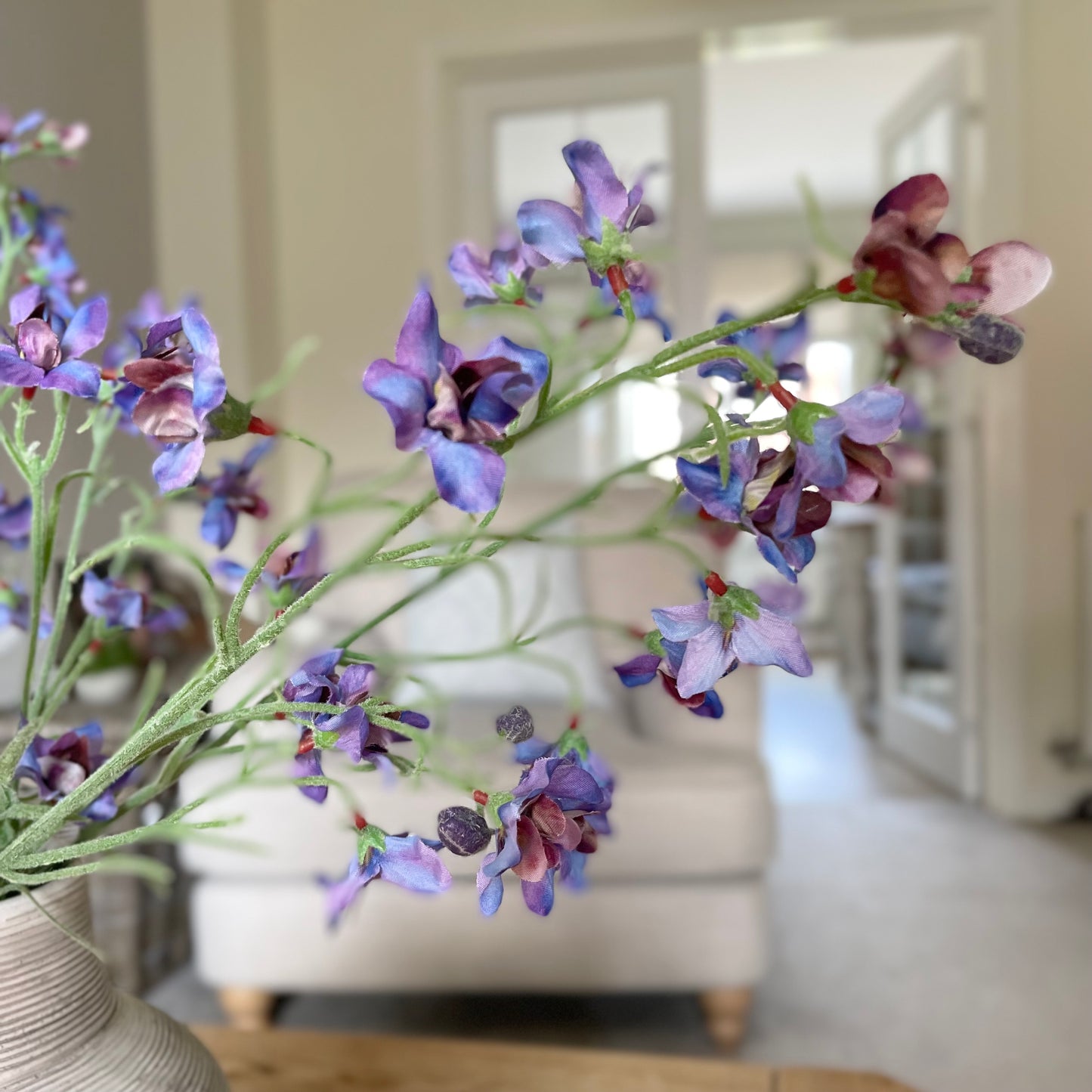 Faux blue and purple delphinium spray, 76 cm tall, styled in a stone vase in a living room.