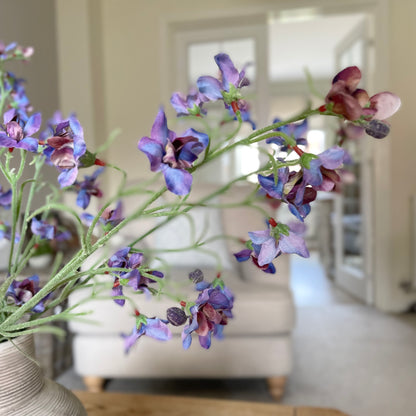 Faux blue and purple delphinium spray, 76 cm tall, styled in a stone vase in a living room.