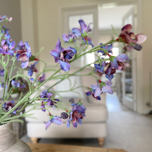 Faux blue and purple delphinium spray, 76 cm tall, styled in a stone vase in a living room.