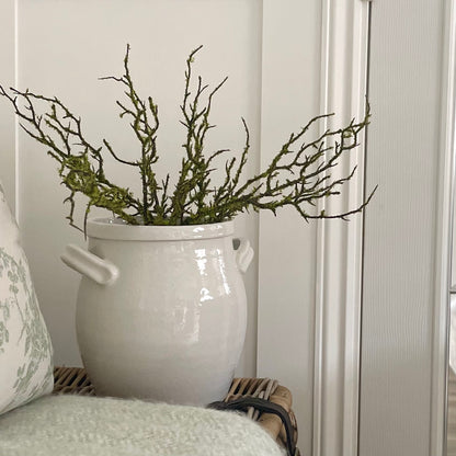 Faux moss covered realistic branch for home decor styling. Standing on wicker trunk and a cosy blanket.