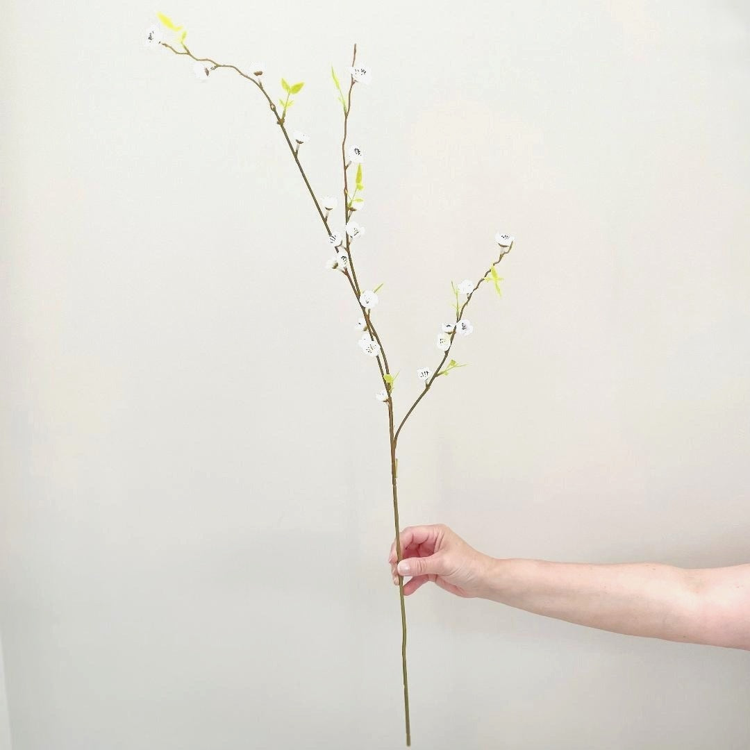 Faux white blossom spray with three stems shown on a white background.
