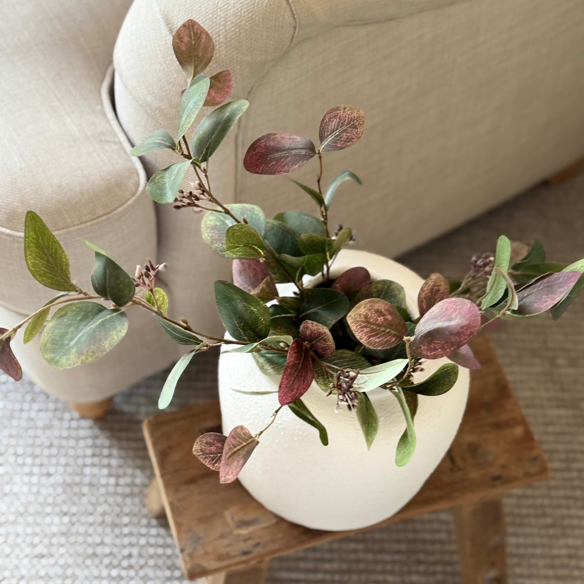 Artificial eucalyptus foliage stem with soft greens and ruby tones, perfect for vase or floral arrangements.