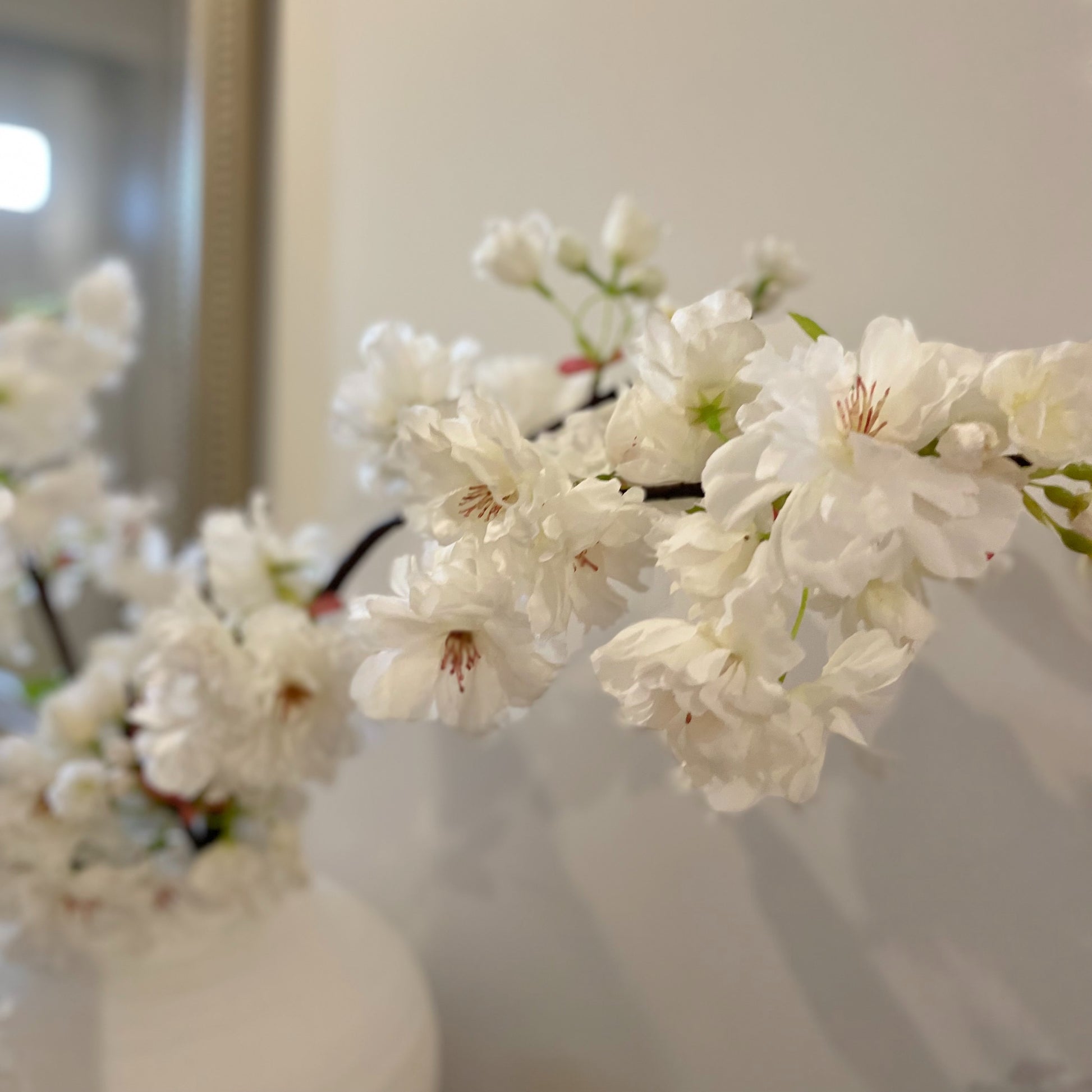 Faux Apple Blossom Stem with delicate white and pink blooms and green leaves, styled in a simple vase for elegant home decor.