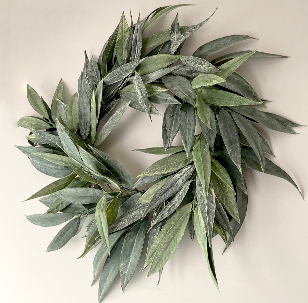 faux green willow wreath hanging on a wall.