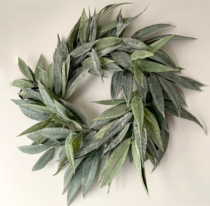 faux green willow wreath hanging on a wall.