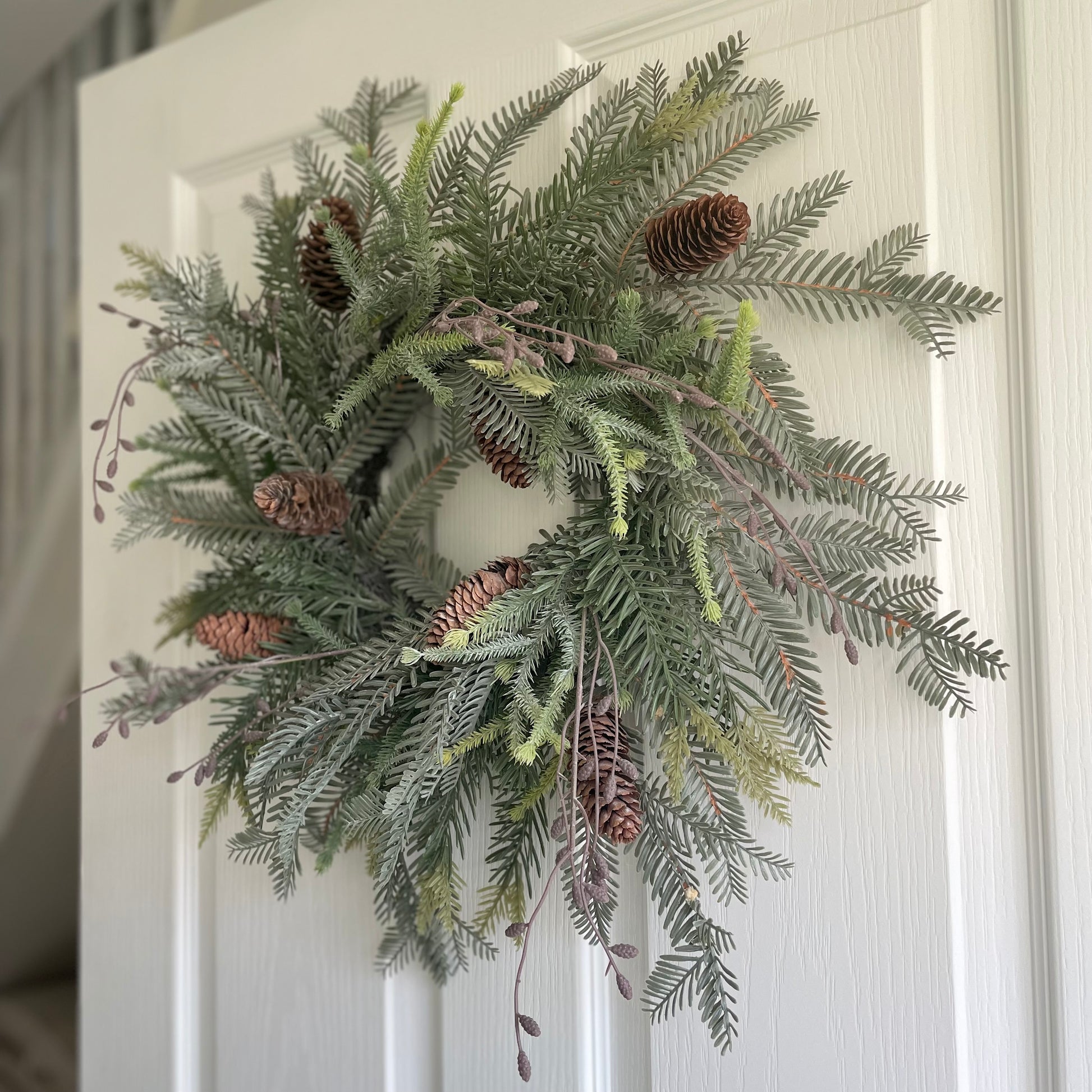 Rustic woodland wreath decorated with ferns and cones.