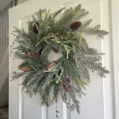 Rustic woodland wreath decorated with ferns and cones.