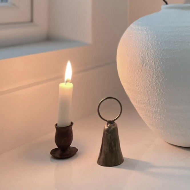 Forged dinner candle holder styled with decorative objects and a white vase on a kitchen island.