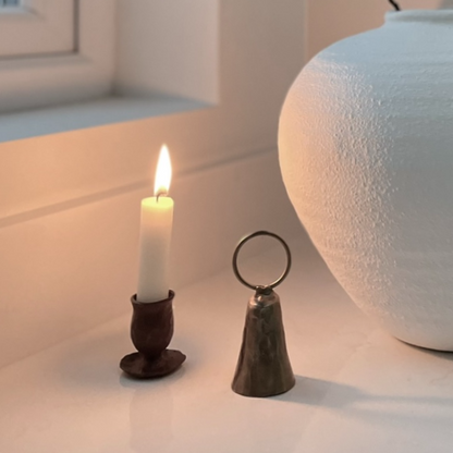 Forged dinner candle holder styled with decorative objects and a white vase on a kitchen island.
