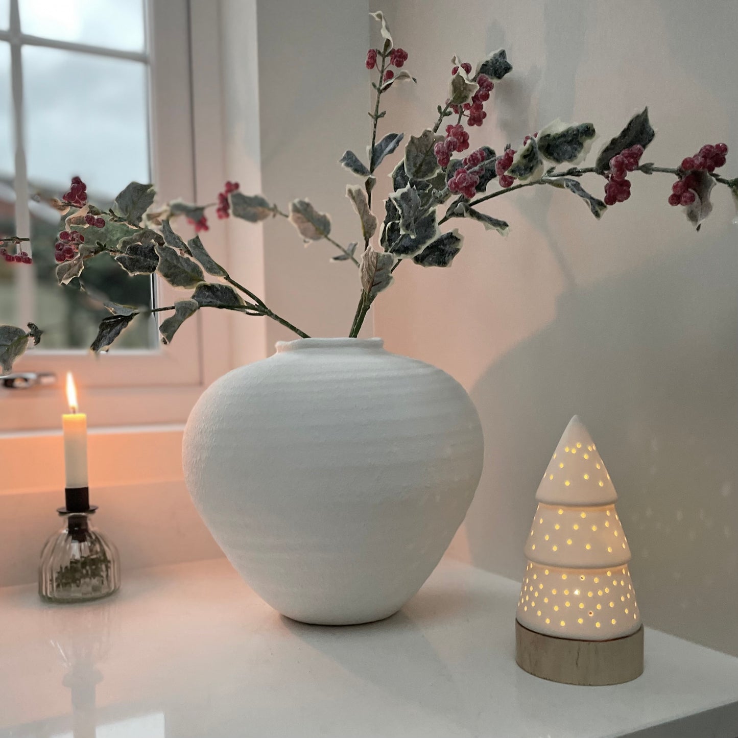 Frosted holly stem with red berries styled in stone white vase, festive faux foliage 68 cm.