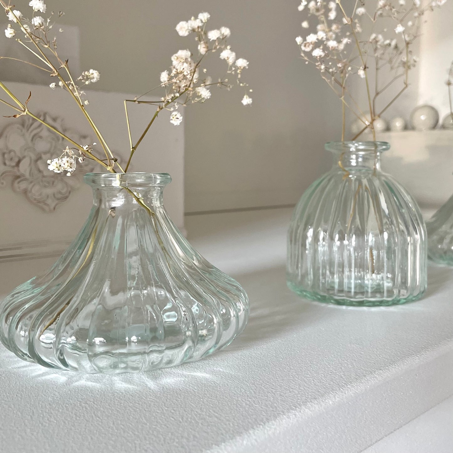 Clear glass bud vase styled with a single stem flower on a wooden table.