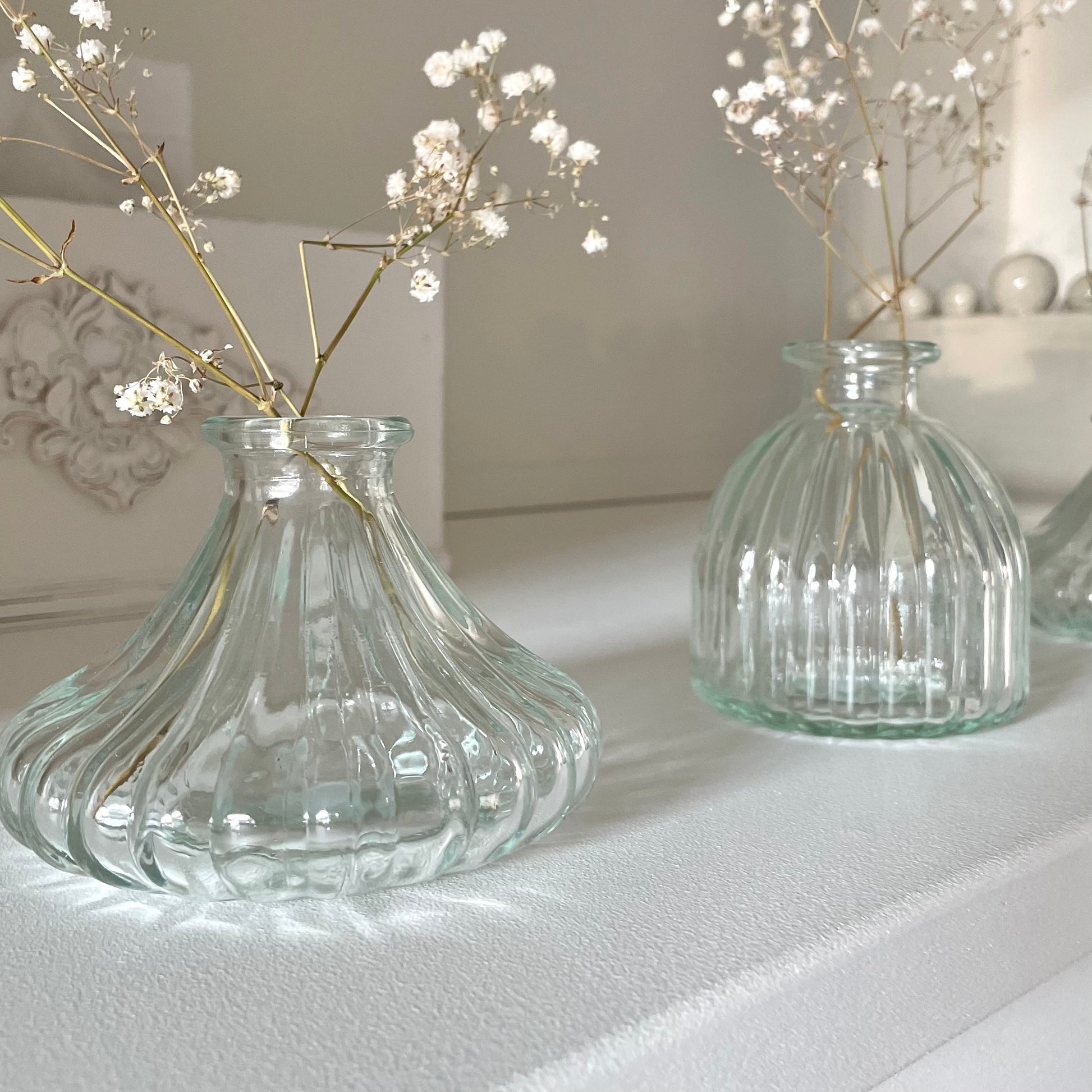 Clear glass bud vase styled with a single stem flower on a wooden table.