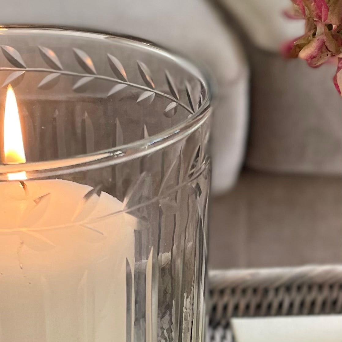 Close up of elegant decorative glass  hurricane lantern. Styled on a rattan tray in a cosy living room.
