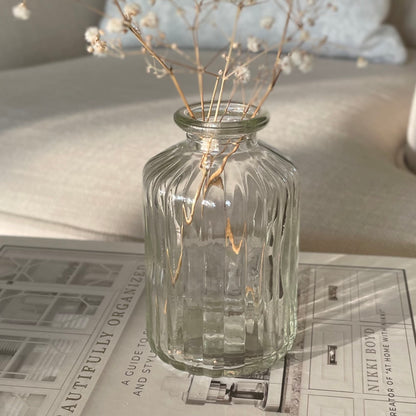 decorative glass bud vase styled on a book with dried gypsophila.