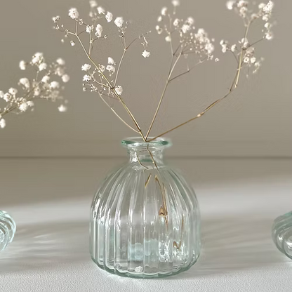 Clear glass bud vase styled with a single stem flower on a wooden table.