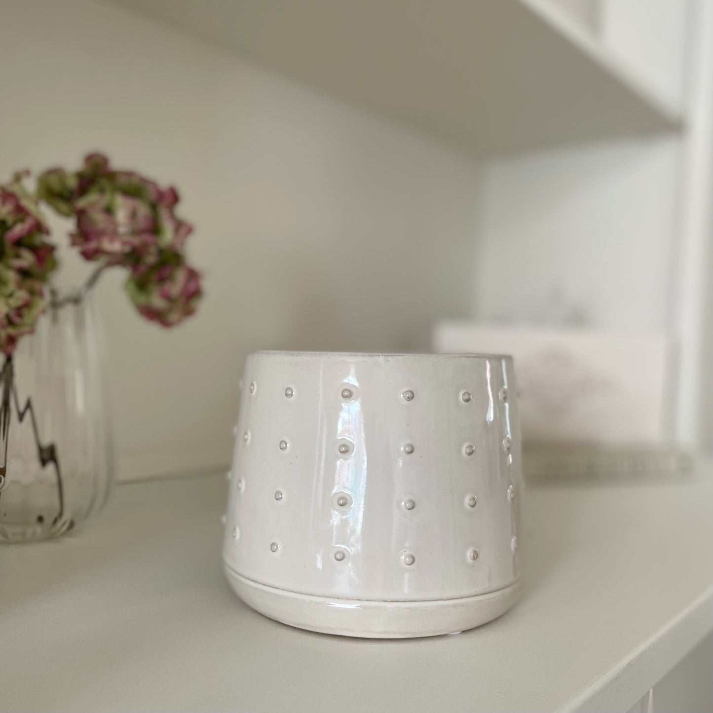 Glazed ceramic pot with embossed bobble pattern styled on a shelf.