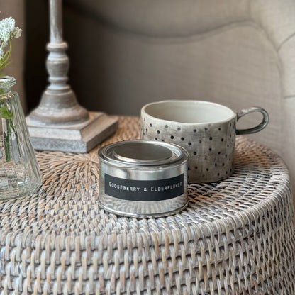 Scented candle and mug candle holder on a rattan table and lamp.