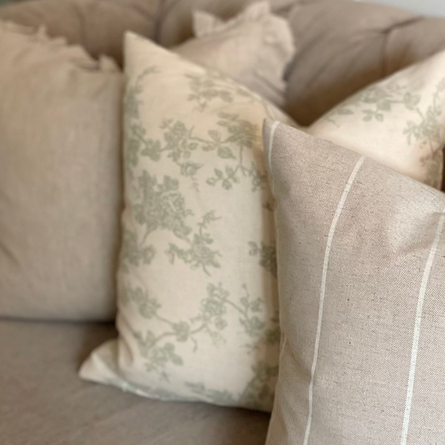 Decorative cushions on a beige sofa with floral prints and stripes.