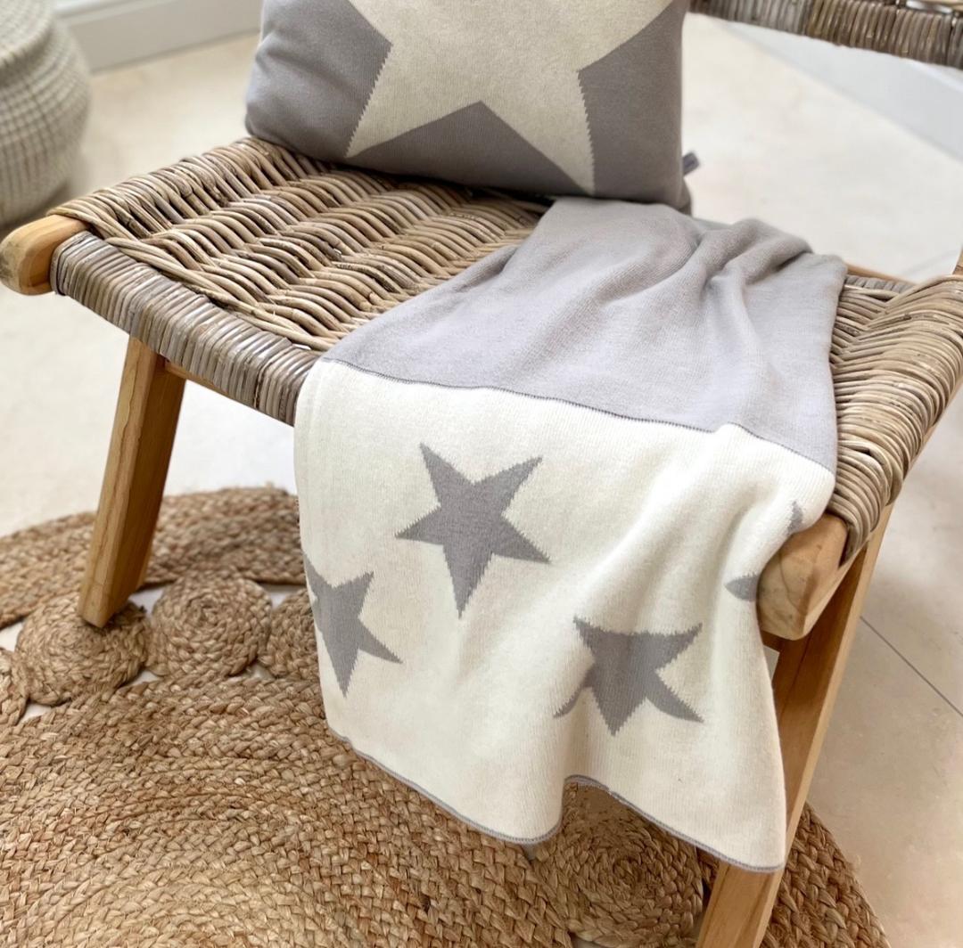 grey and cream soft throw with reversible star detail. Styled on chair with cushion.