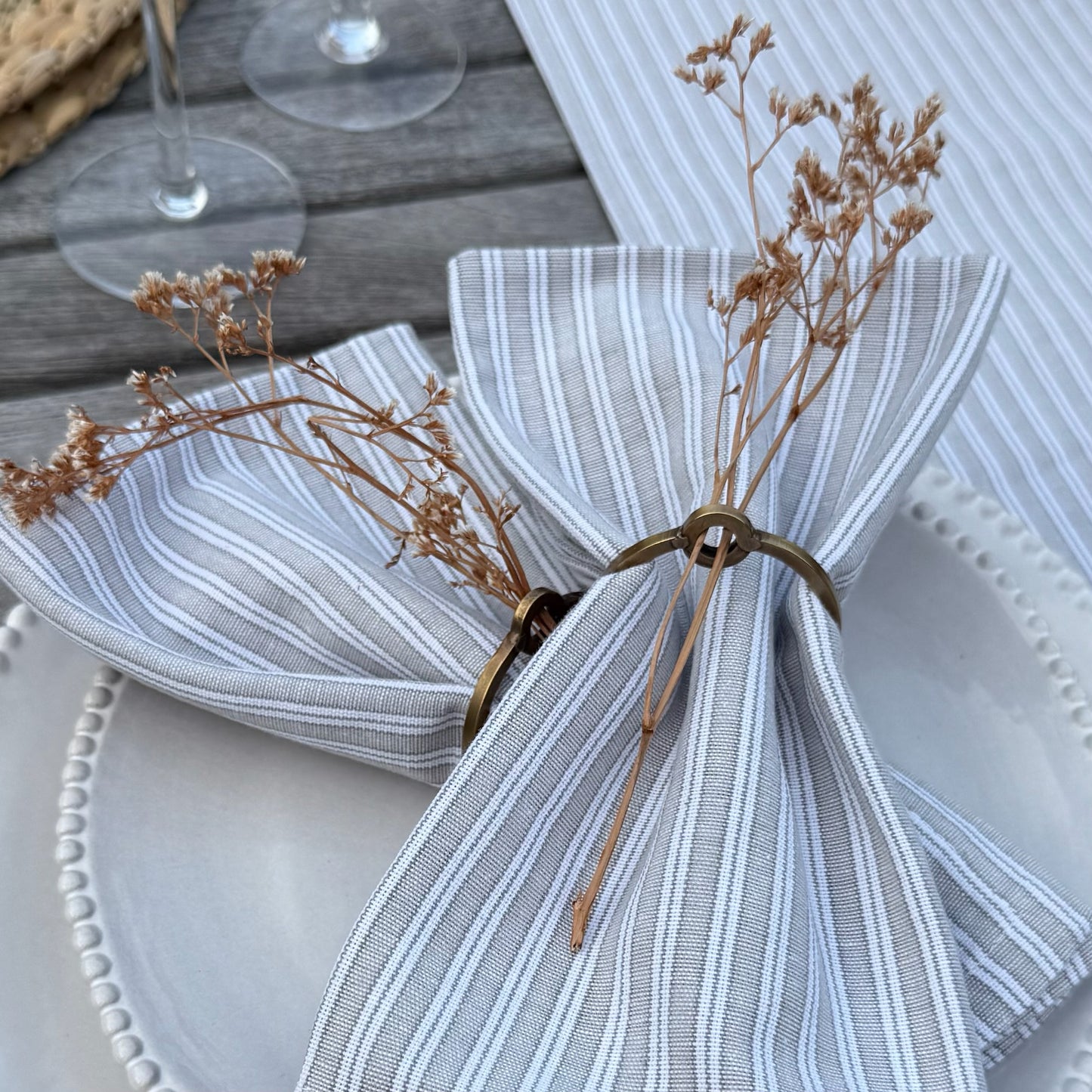Natural cotton napkins in classic grey stripes, bringing simple, washable elegance to a calm and inviting tablescape.