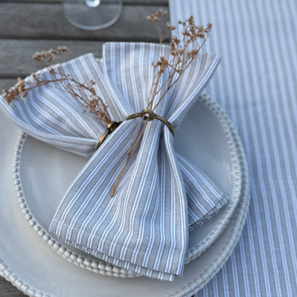Striped napkin folded on a plate with decorative elements on a matching tablecloth.