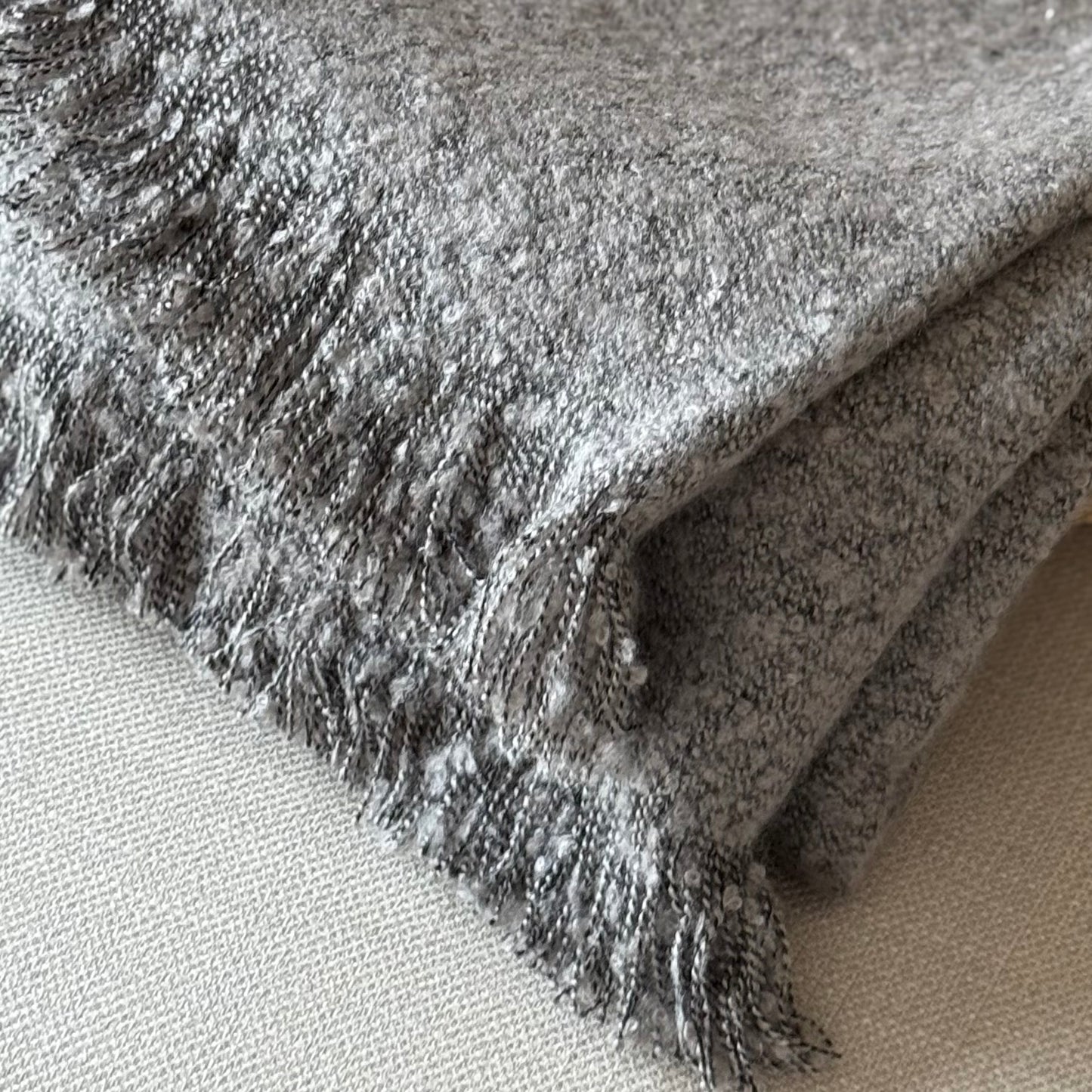 Close-up of a textured gray fabric with frayed edges on a neutral background.