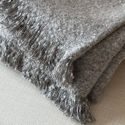Close-up of a textured gray fabric with frayed edges on a neutral background.