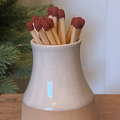 Handmade ceramic milk bottle match holder with long safety matches and hidden striker pad. 