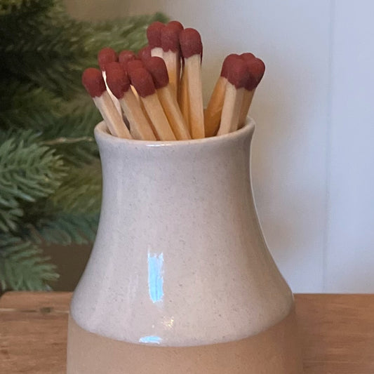 Handmade ceramic milk bottle match holder with long safety matches and hidden striker pad. 