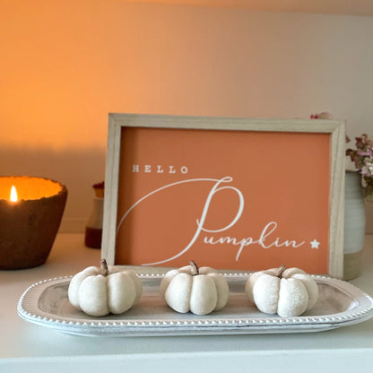 Wooden “Hello Pumpkin” sign styled with autumn accessories. With a candle lit on a shelf with velvet mini pumpkins.