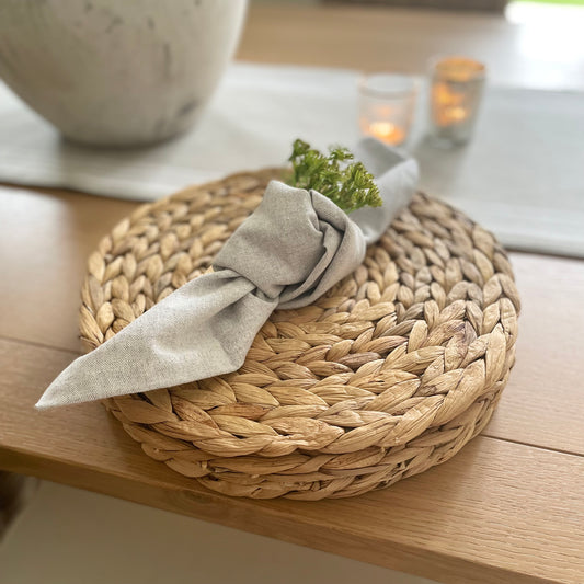 Round woven water hyacinth placemat showing its tight, natural weave and rustic organic texture on a styled table.