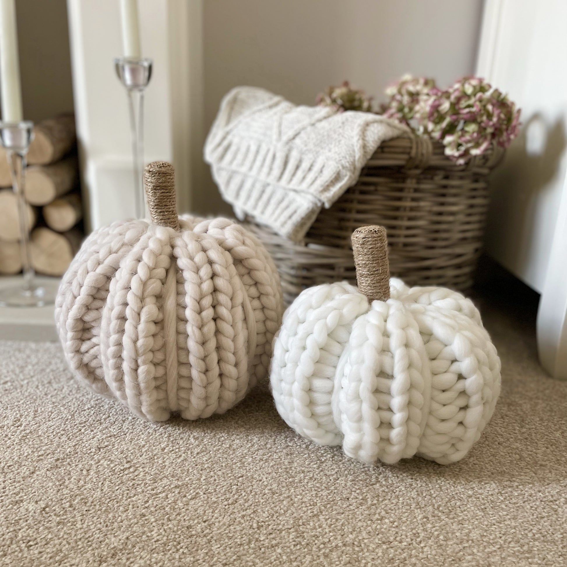 White and beige chunky knitted pumpkins with twine stalks styled next to a rustic basket with cable knit throw and hydrangea flowers