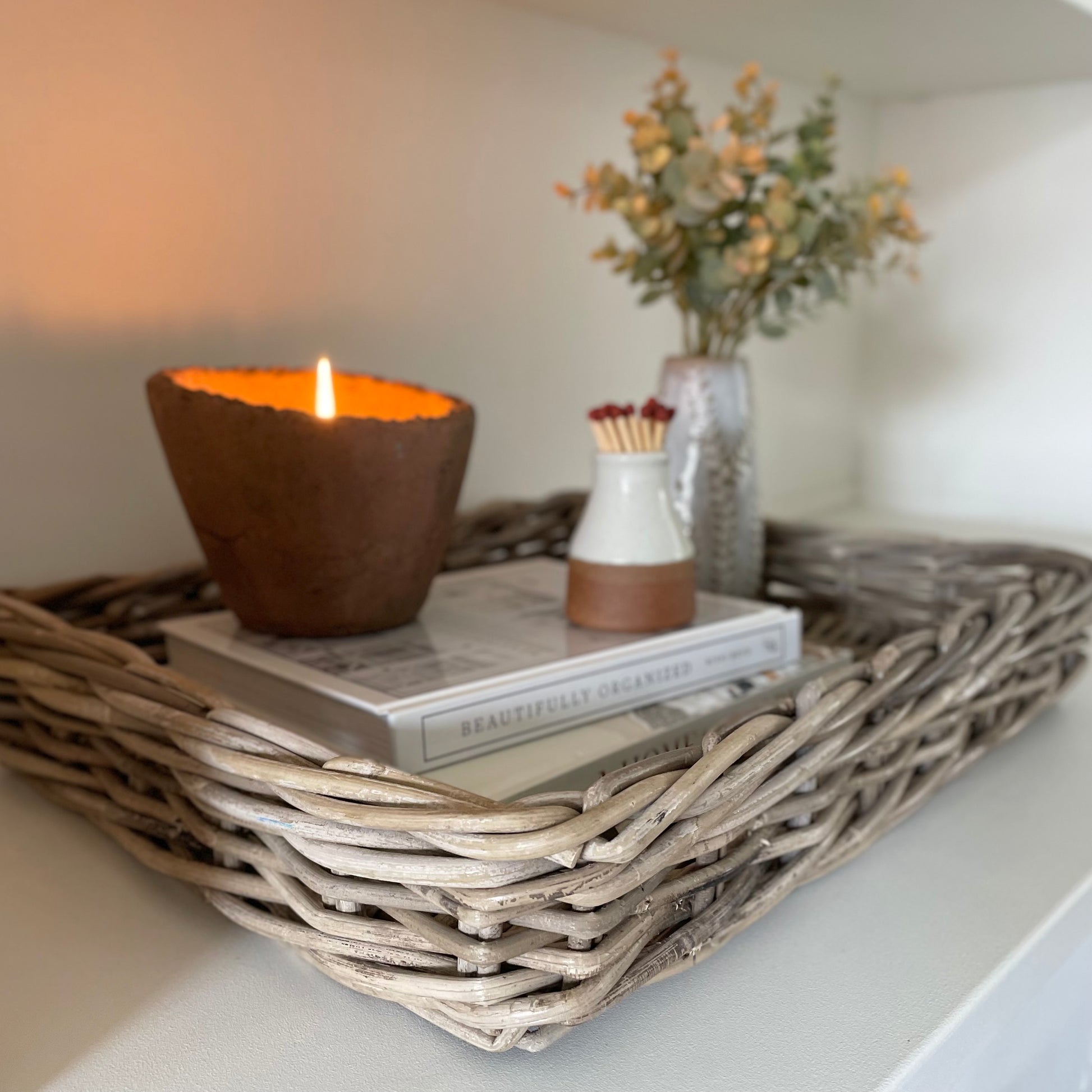Handwoven natural rattan tray holding decorative items, adding warmth and texture to a neutral interior.