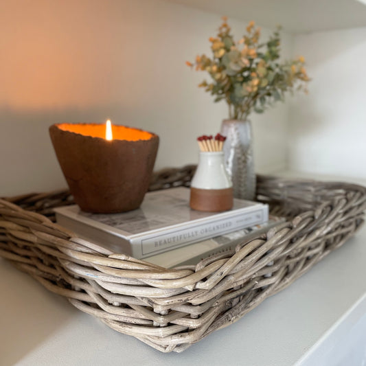 Handwoven natural rattan tray holding decorative items, adding warmth and texture to a neutral interior.